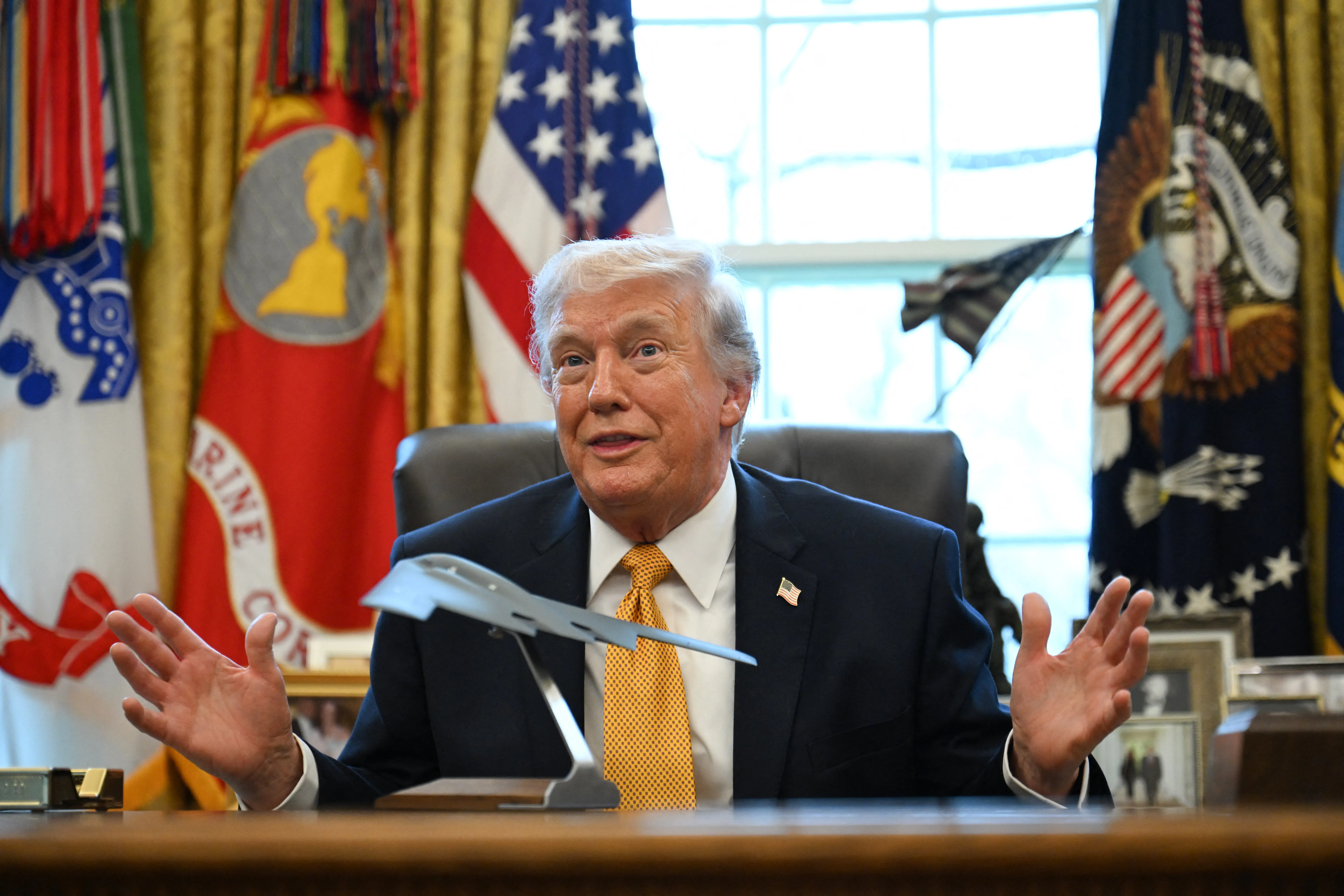 Trump in the Oval Office with a model of a stealth bomber on the Resolute Desk