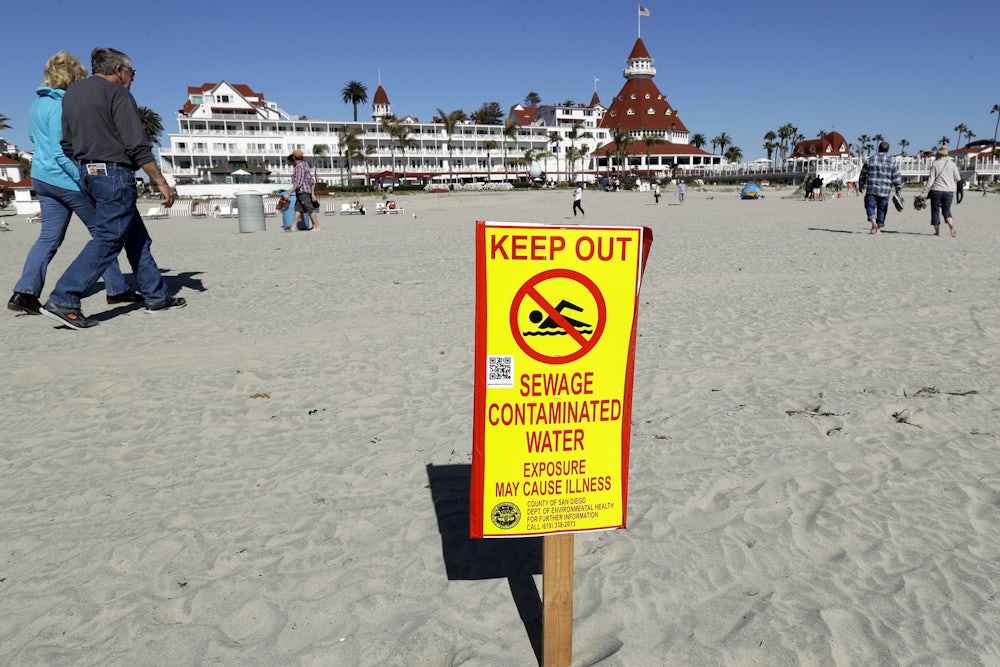 A photograph of a sign in front of the iconic Hotel del Coronado in Coronado, California, warns of contaminated ocean water.