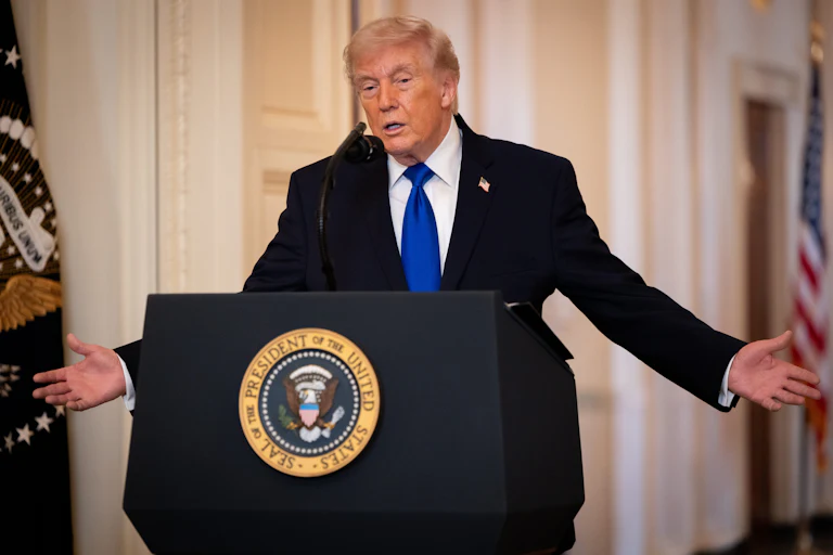 Donald Trump holds his arms out to the side while speaking at a podium