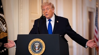 Donald Trump holds his arms out to the side while speaking at a podium