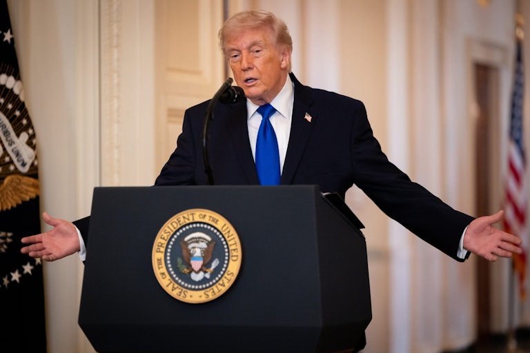 Donald Trump holds his arms out to the side while speaking at a podium