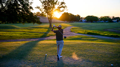 A man swings his golf club at East Potomac Golf Links