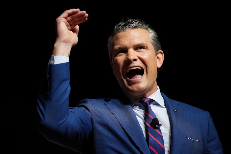War Secretary Pete Hegseth raises his hand above his head while speaking to military leaders at Quantico