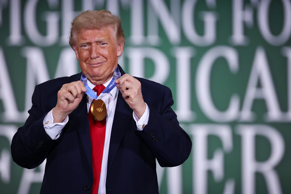 Donald Trump grins while sporting a gold medal