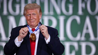 Donald Trump grins while sporting a gold medal