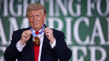 Donald Trump grins while sporting a gold medal