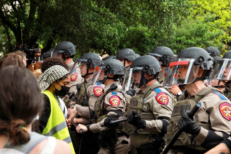 Police officers stand opposite protesters