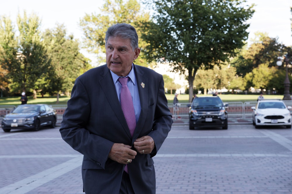 Joe Manchin buttons his jacket while walking.