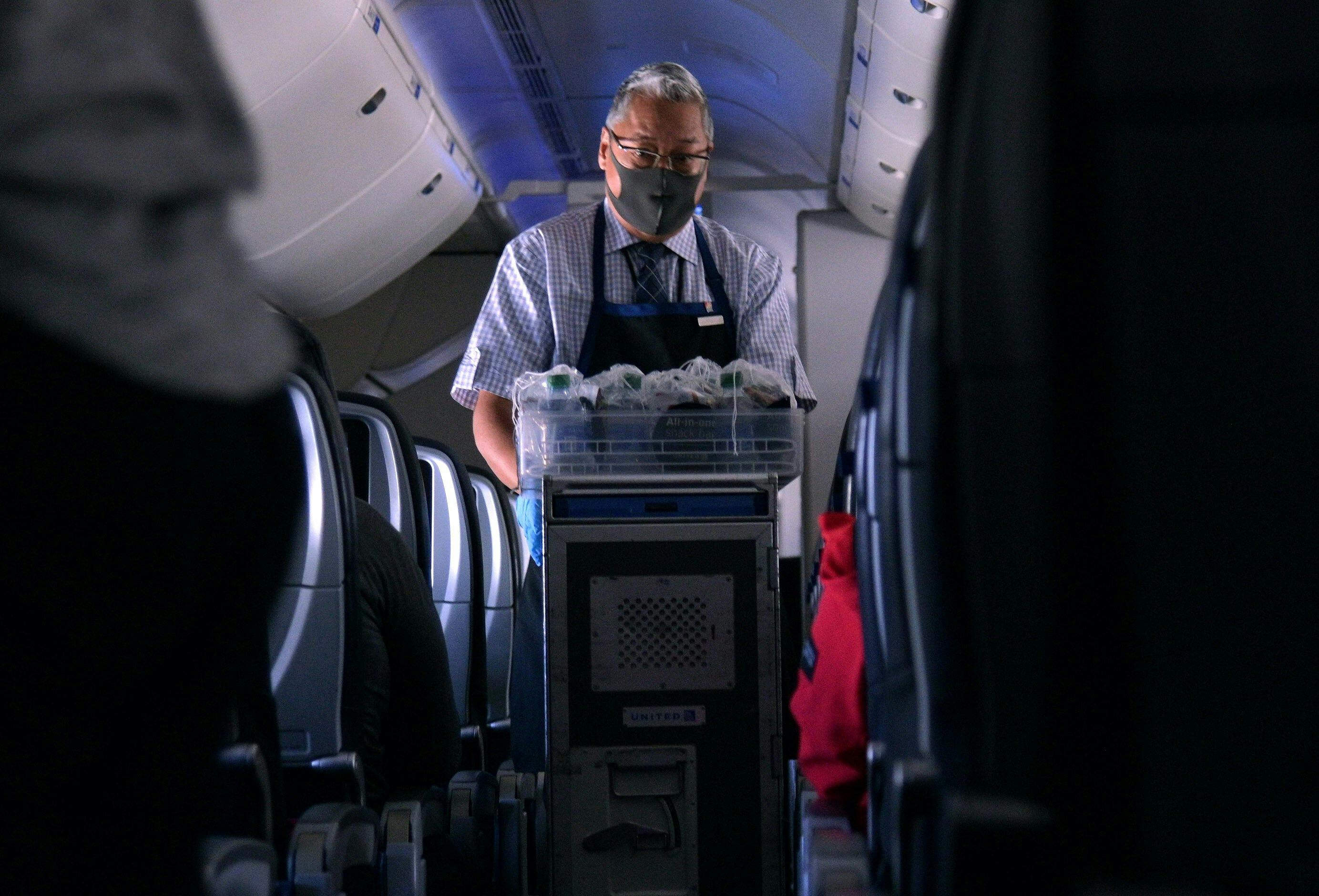 a flight attendant pushes a cart down the aisle of a plane