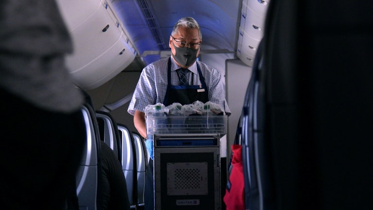 a flight attendant pushes a cart down the aisle of a plane