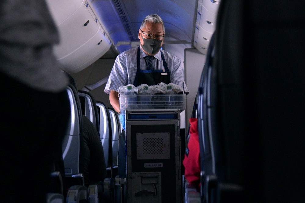 a flight attendant pushes a cart down the aisle of a plane