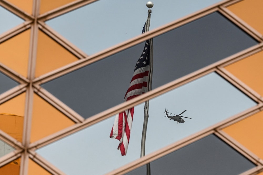 The American flag is reflected on the windows of the U.S. embassy building in Kabul as a helicopter flies away.