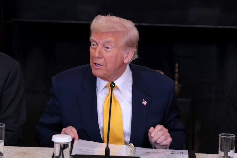 President Donald Trump delivers remarks while seated on a panel