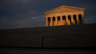 The facade of the U.S. Supreme Court lit by a setting sun, foregrounded by shadows.
