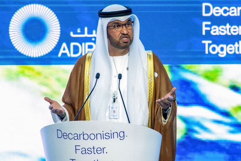 Sultan Ahmed al-Jaber stands at a podium labeled "Decarbonising. Faster."