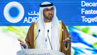 Sultan Ahmed al-Jaber stands at a podium labeled "Decarbonising. Faster."