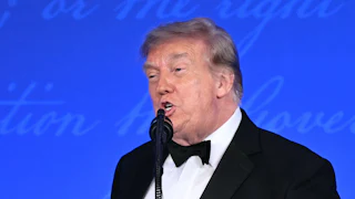 Donald Trump speaks into a microphone at the White House Correspondents' Dinner.
