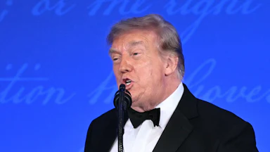 Donald Trump speaks into a microphone at the White House Correspondents' Dinner.