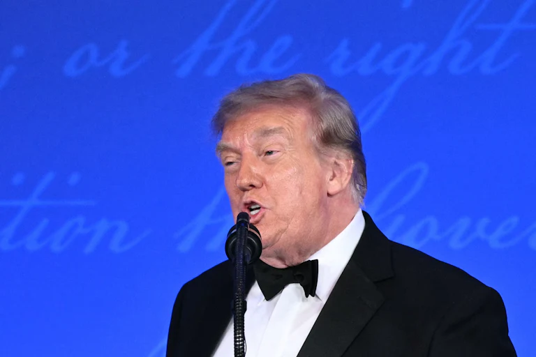 Donald Trump speaks into a microphone at the White House Correspondents' Dinner.