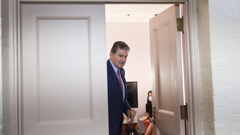 West Virginia Senator Joe Manchin stands in a doorwar as he leaves a meeting.