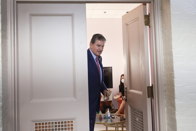 West Virginia Senator Joe Manchin stands in a doorwar as he leaves a meeting.