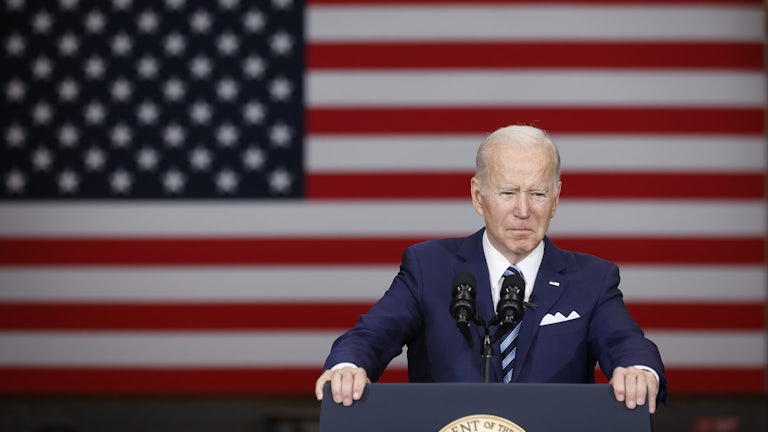 Joe Biden stands behind a lectern in front of the U.S. flag.