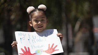 A child holds up a sign saying "my future is in your hands."