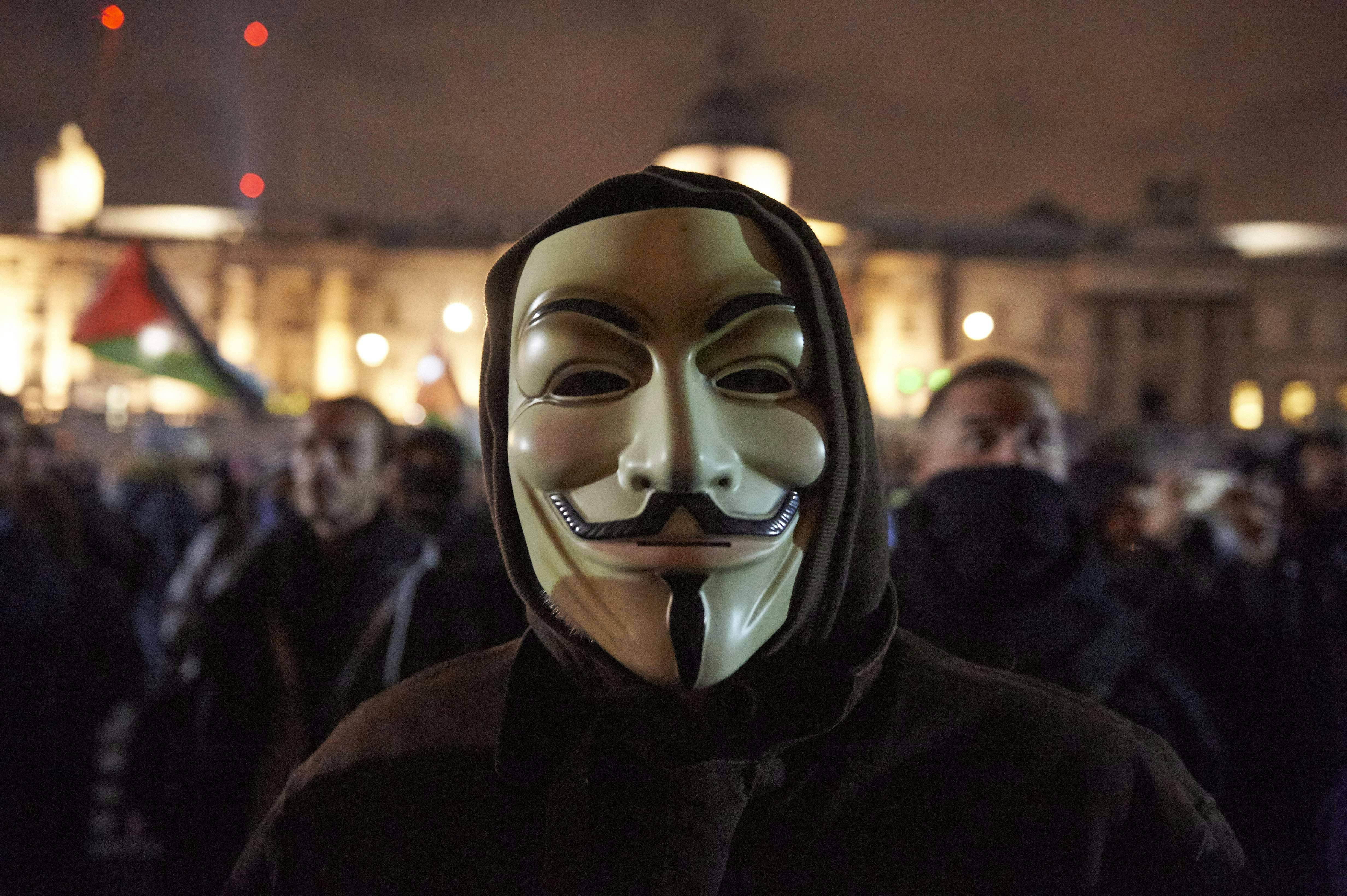 Man wearing a Guy Fawkes mask in the street at nighttime at the “Million Masks March,” organized by the group Anonymous, in London on November 5, 2017