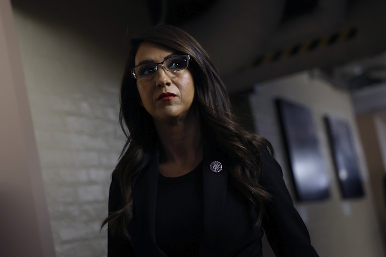 Lauren Boebert stands in a hallway, partially obscured by shadow