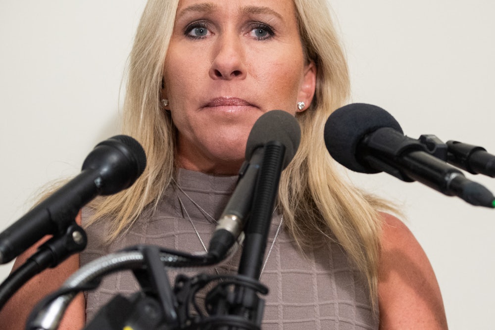 A close up of Marjorie Taylor Greene, surrounded by microphones.