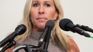 A close up of Marjorie Taylor Greene, surrounded by microphones.