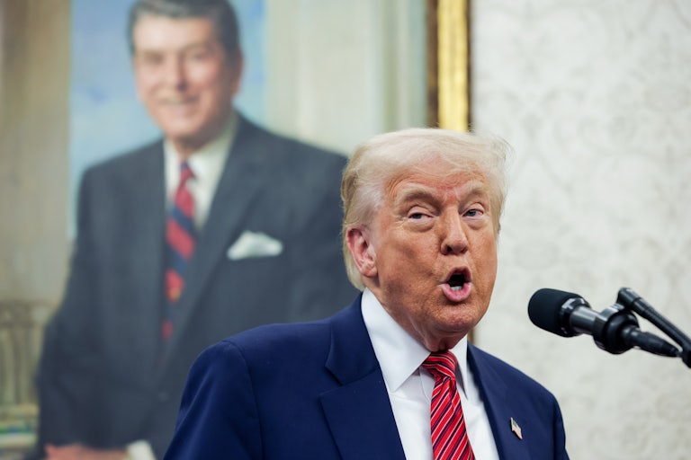 Donald Trump speaks into a microphone in the Oval Office
