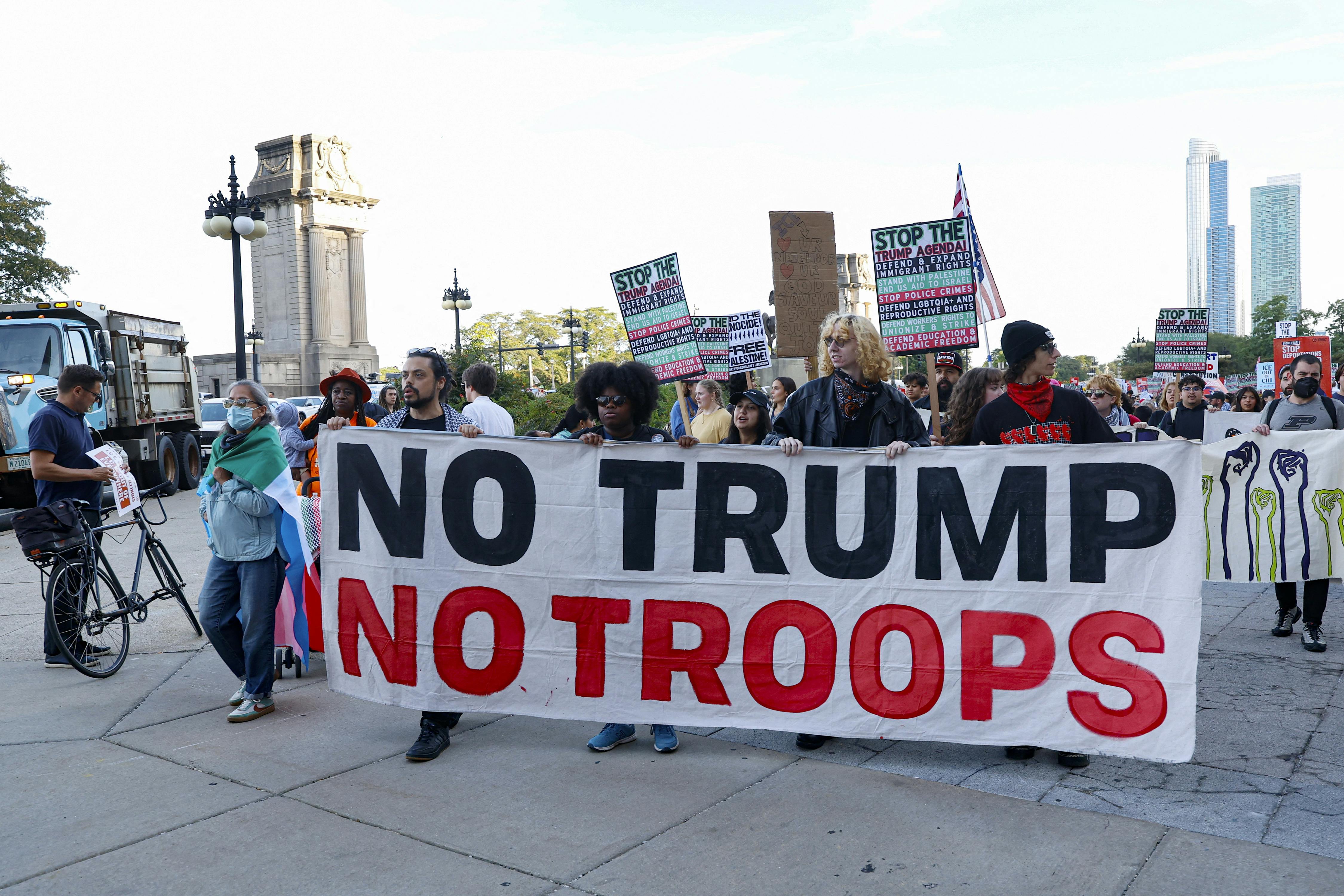 People hold a banner that says, "No Trump, no troops" at a protest against the presence of the National Guard in Chicago