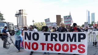 People hold a banner that says, "No Trump, no troops" at a protest against the presence of the National Guard in Chicago