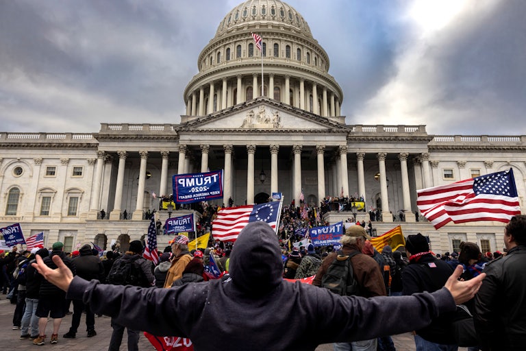 A man stands with outstretched hands before a mob of rioters attacking the U.S. Capitol.