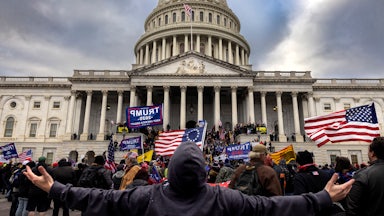 A man stands with outstretched hands before a mob of rioters attacking the U.S. Capitol.