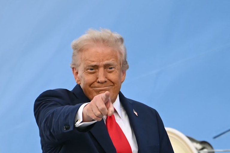 Donald Trump smiles and points while boarding Air Force One