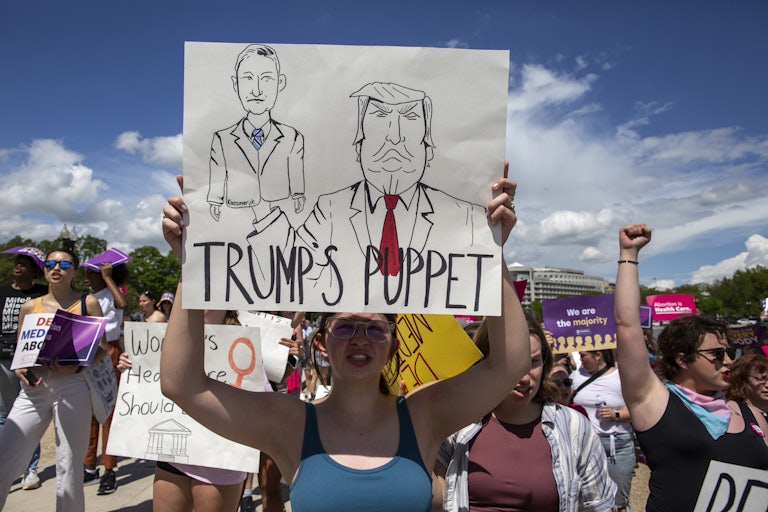 An abortion rights activist holds a sign with a sketch of Judge Matthew Kacsmaryk and Donald Trump