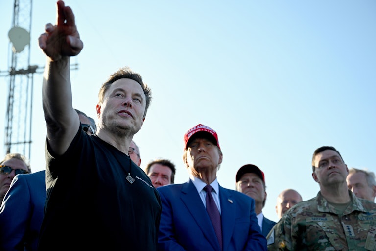 Elon Musk points off into the distance as Trump and others watch.