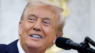 Donald Trump smiles while standing at a podium