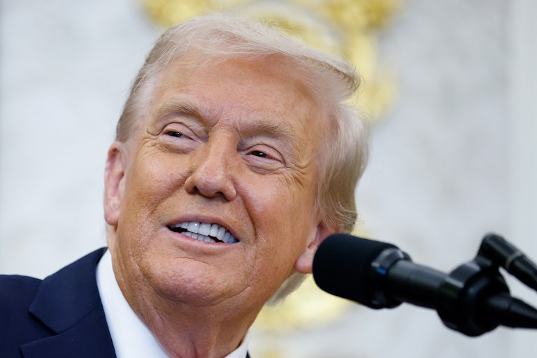 Donald Trump smiles while standing at a podium