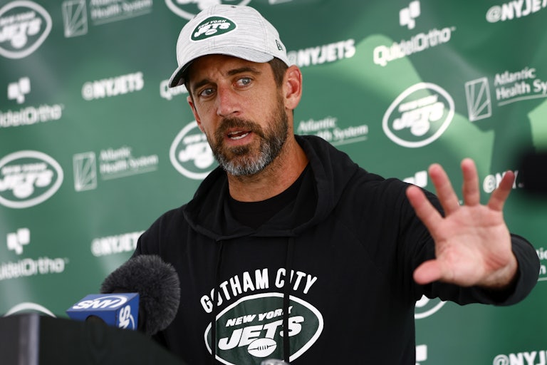 Aaron Rodgers speaks at a mic and splays his hand out