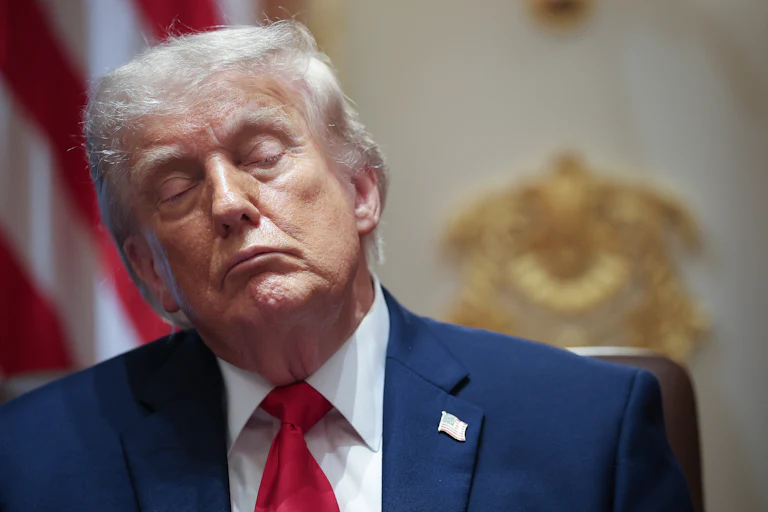 Donald Trump sits with his eyes closed at his desk in the Oval Office