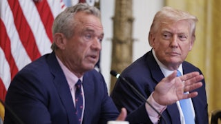Robert F. Kennedy Jr. sits next to Donald Trump and speaks into microphone while gesturing