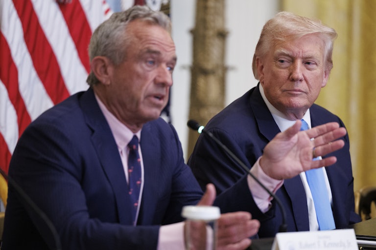 Robert F. Kennedy Jr. sits next to Donald Trump and speaks into microphone while gesturing