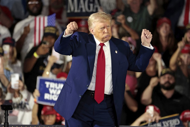 Donald Trump holds up his fists while onstage at a rally