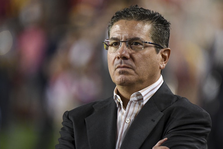 Daniel Snyder crosses his arms as he stands on the sideline of an NFL game