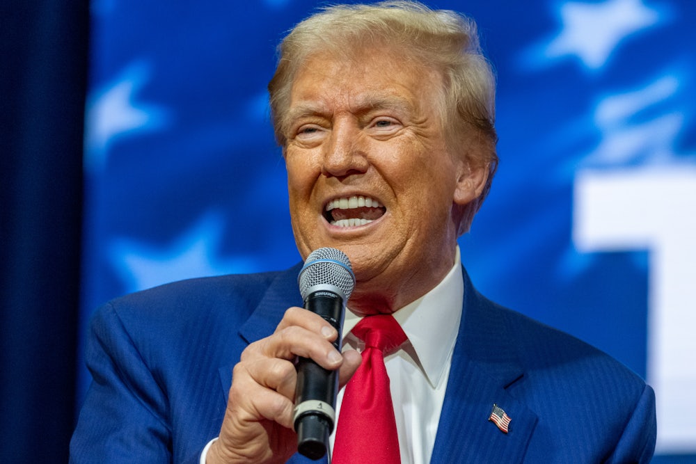 Donald Trump holds up a microphone and speaks into it