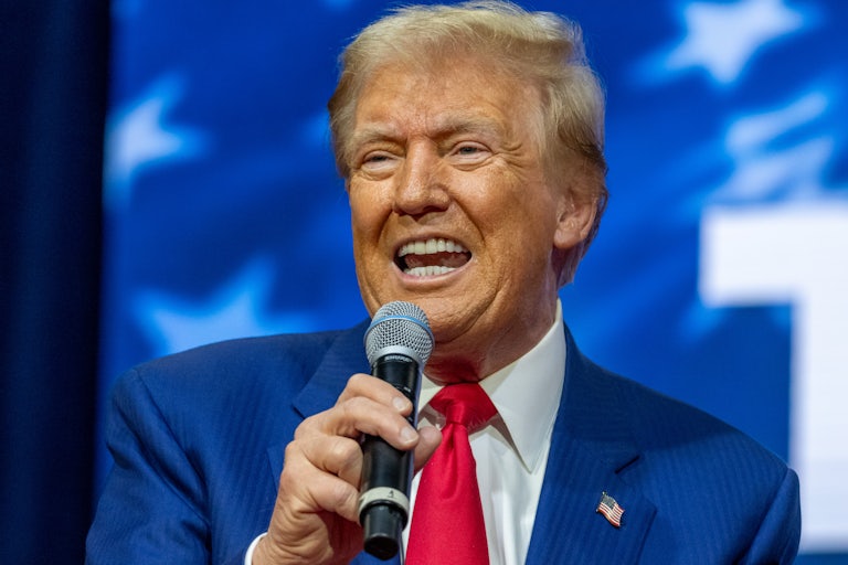 Donald Trump holds up a microphone and speaks into it