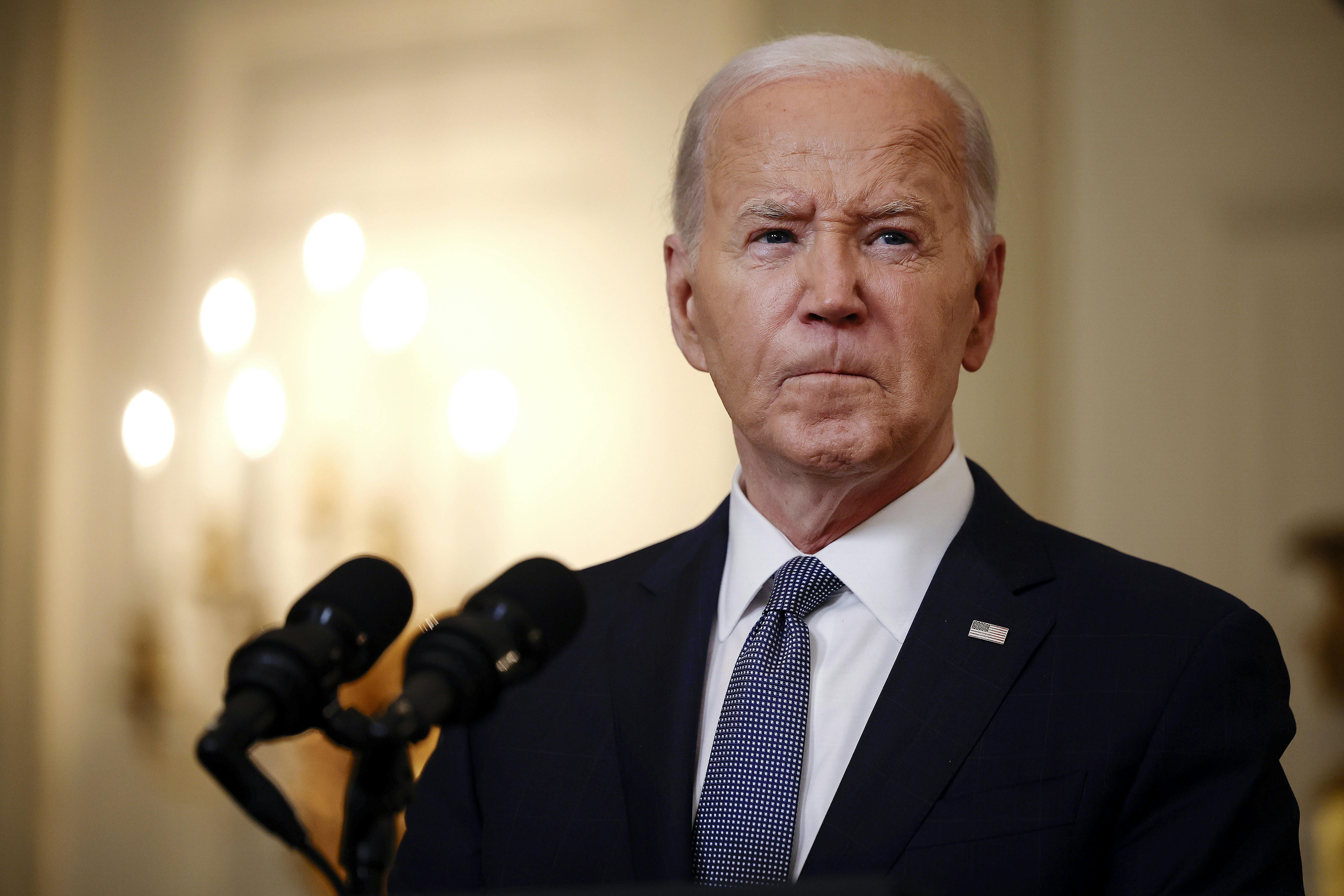 Joe Biden purses his lips while giving a speech behind a lectern. 